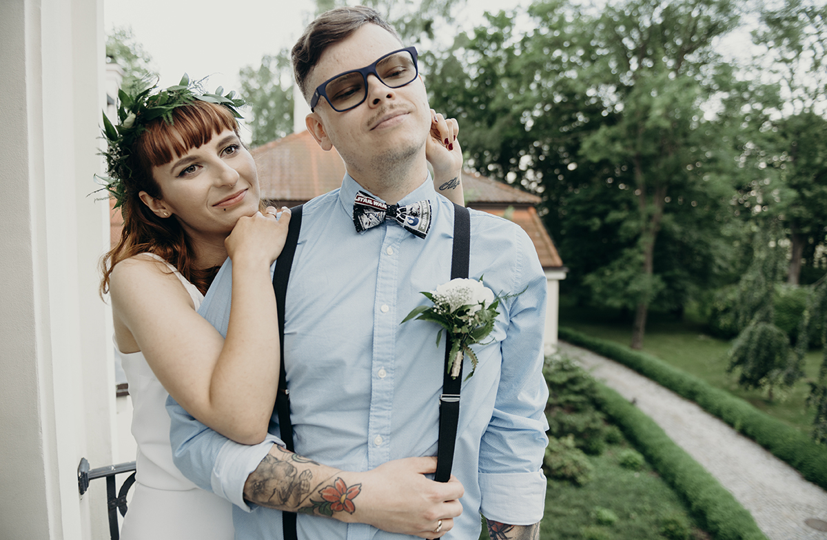 Pan Młody w stylowych okularach, niebieskiej koszuli i granatowych szelkach na weselu