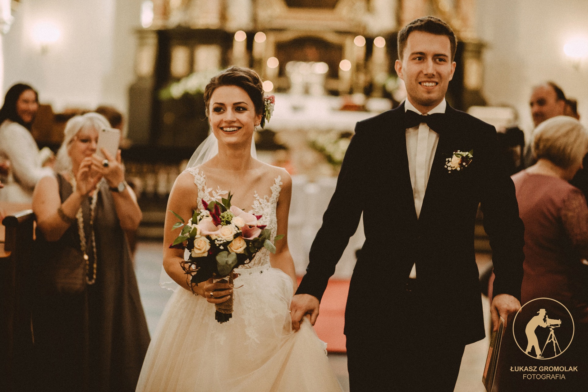 Elegancki Pan Młody w czarnym garniturze i czarnej muszce w kościele
