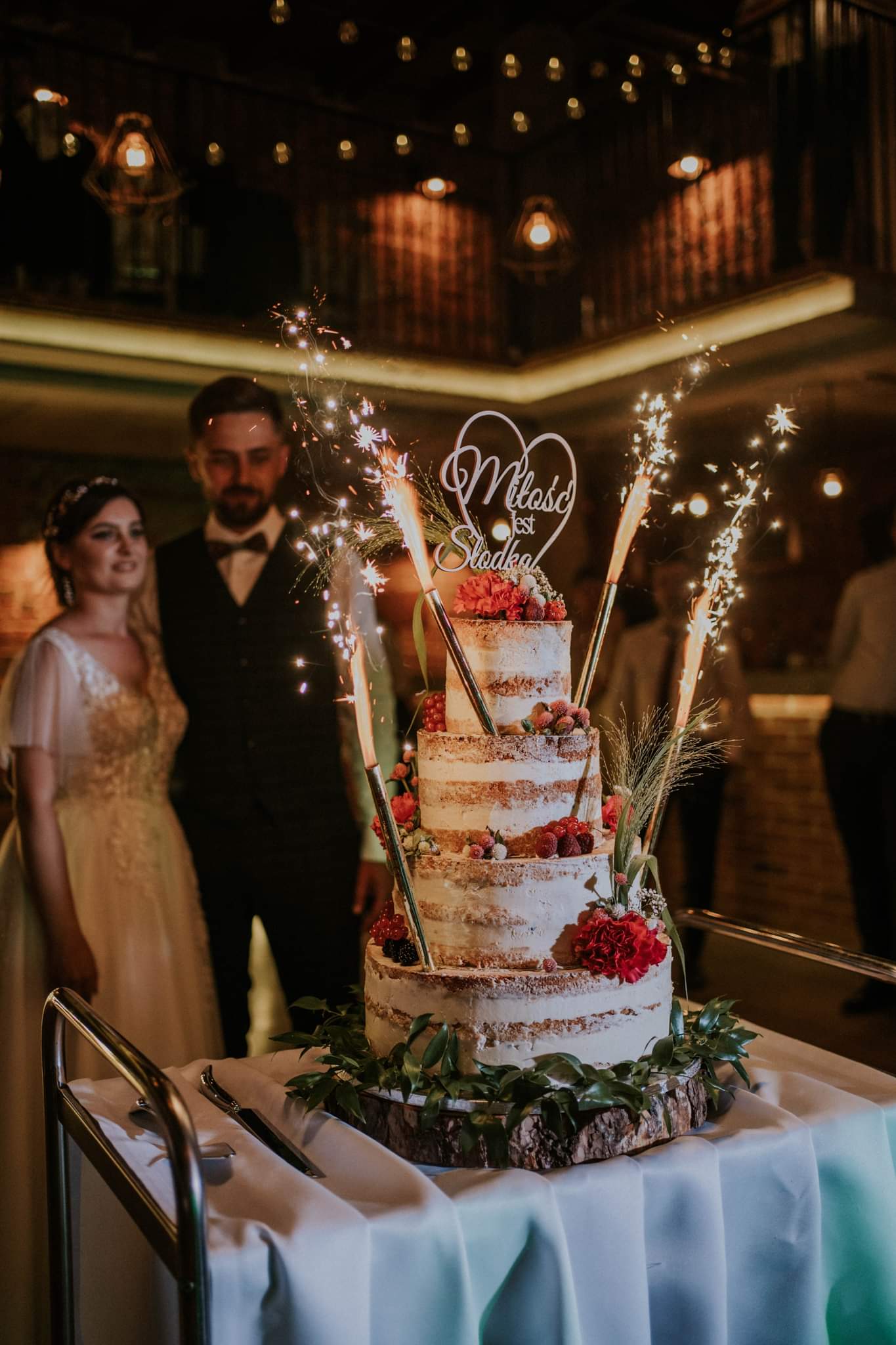 tort weselny naked cake z czerwonymi kwiatami i drewnianym topperem