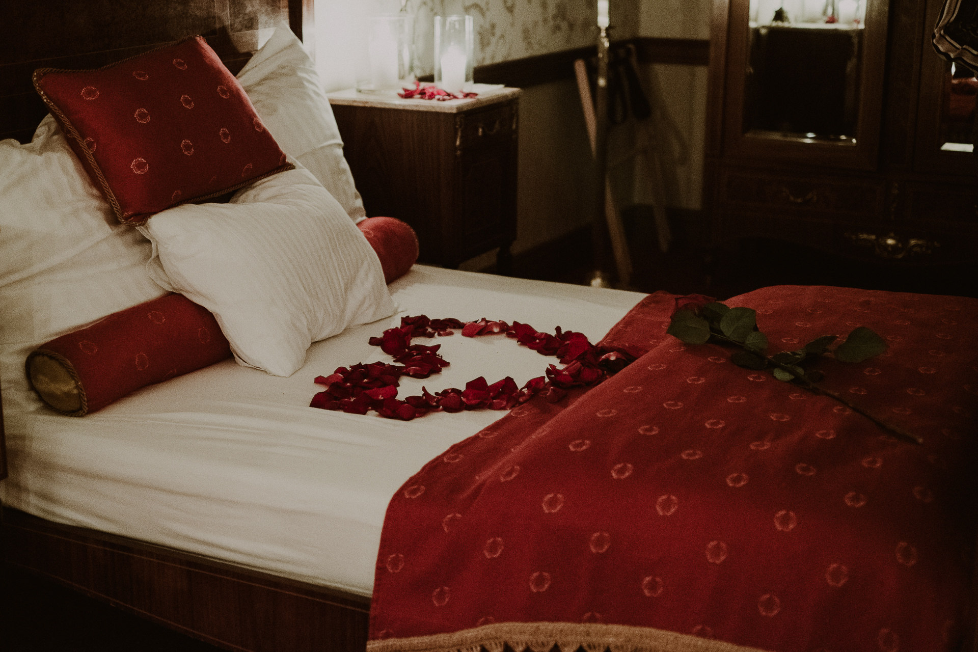 łóżko w płatkami róż w kształcie serca w pokoju hotelowym dla narzeczonych podczas sesji ślubnej