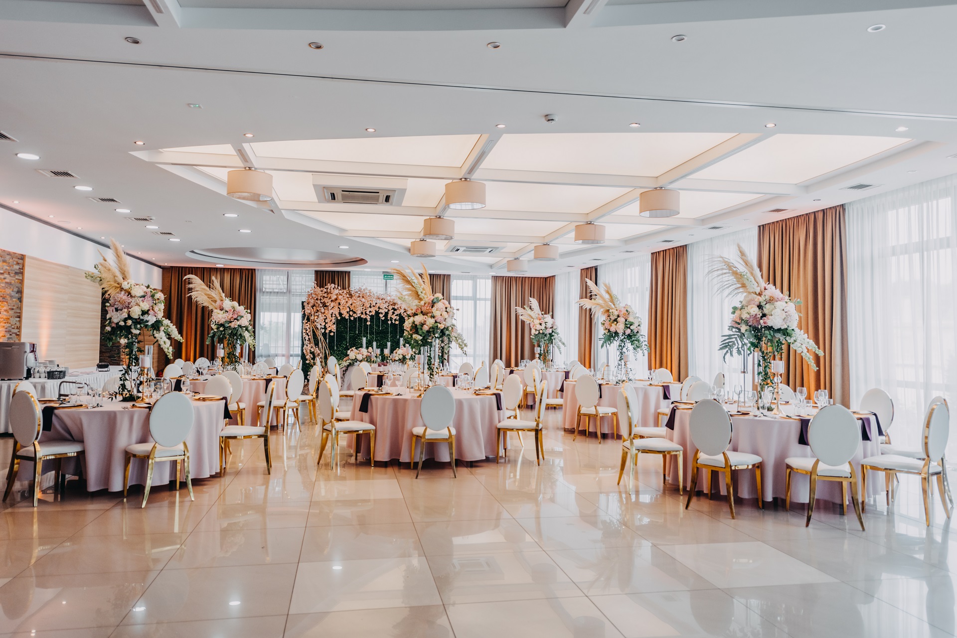 elegancka sala weselna wysokie kompozycje kwiatowe na stołach weselnych