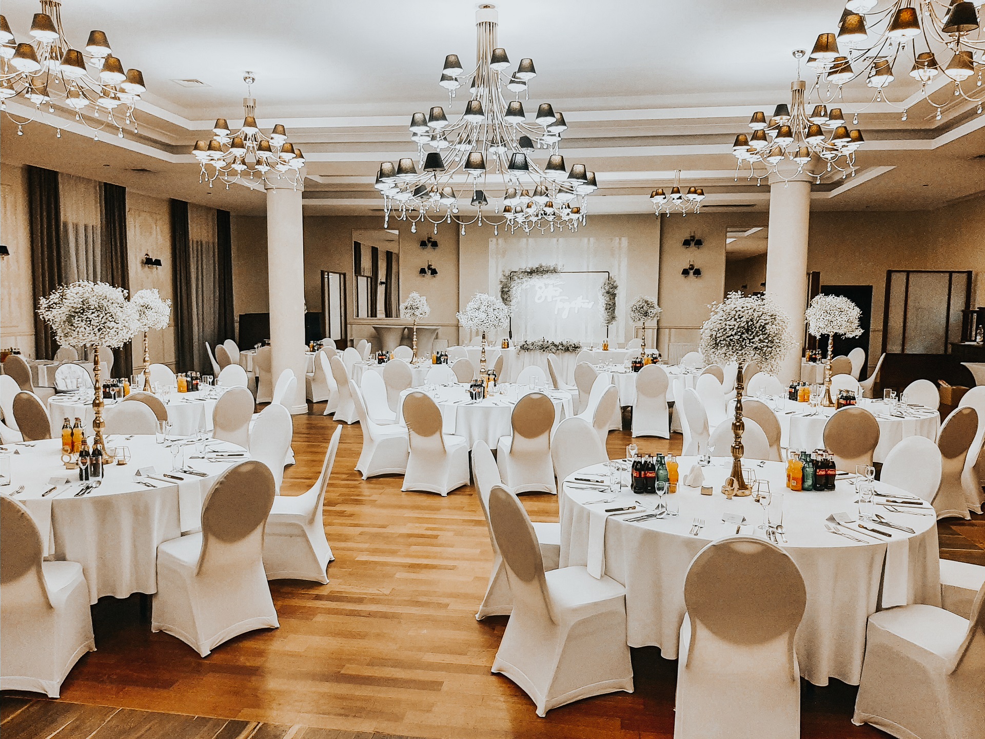 białe eleganckie okrągłe stoły sala weselna wysokie kompozycje z gipsówki trendy ślubne