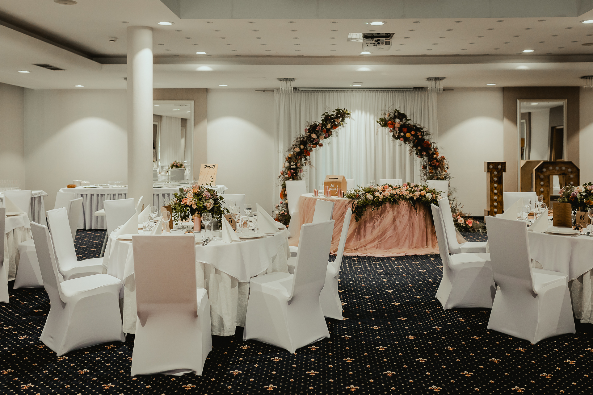 elegancka sala weselna z okrągłymi stołami z różowymi dekoracjami reportaż ślubny  