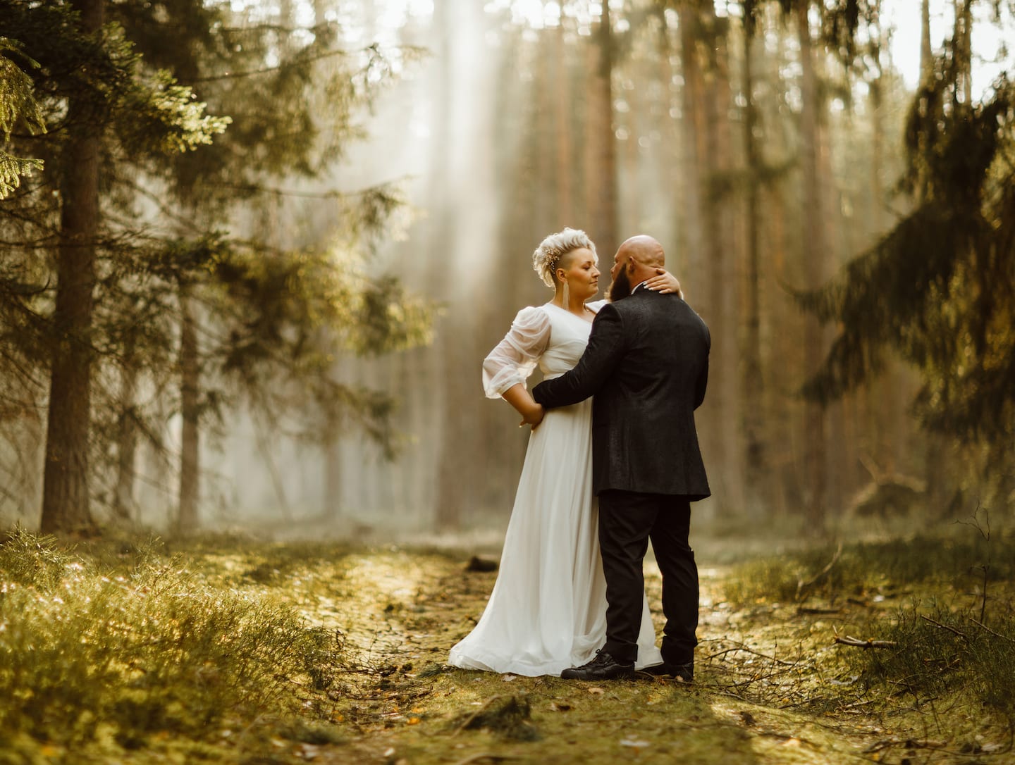 sesja ślubna w lesie panna młoda z krótkimi włosami blond w zwiewnej sukni ślubnej promienie słońca