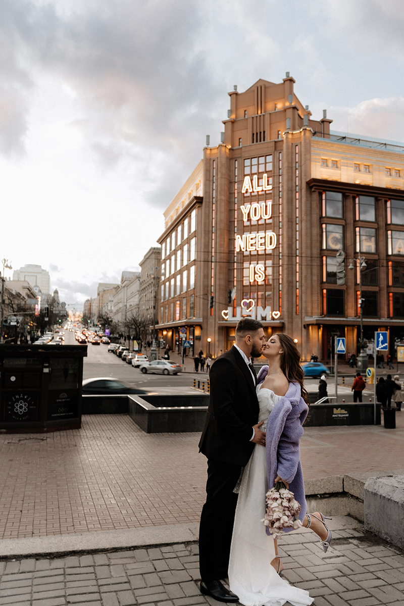 jesienna sesja ślubna w mieście na tle budynku z cegły z napisem All you need is love