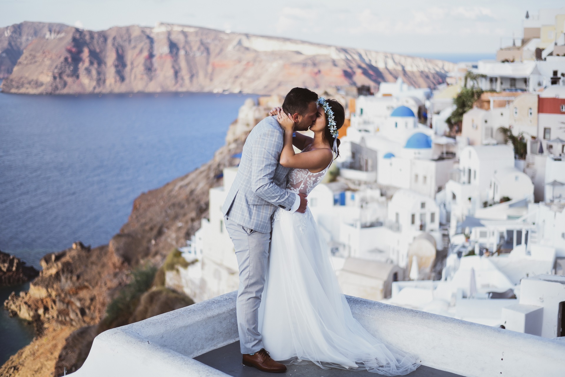ślub na Santorini całująca się para młoda na tle morza i białych domów